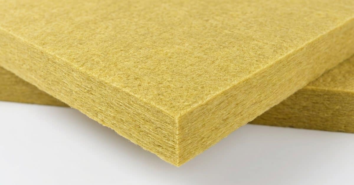 Panneau semi-rigide de laine de verre jaune vu en gros plan montrant la surface fibreuse compacte et la tranche découpée révélant la structure dense des fibres minérales